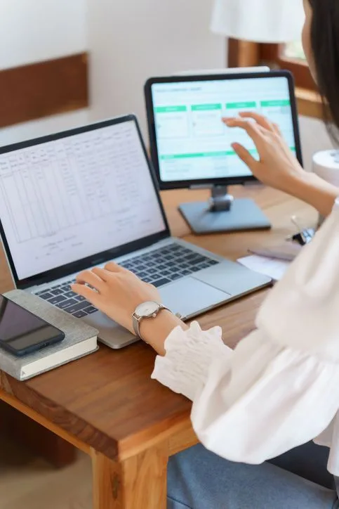 Personne consultant un logiciel de GED sur ordinateur portable et écran